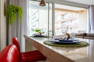 a kitchen with a counter with plates and a red chair at AP Df Plaza varandão in Brasília