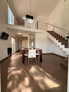 a dining room with a table and chairs and stairs at Complejo del Jagüel Cabaña Virginia in Santa Teresita