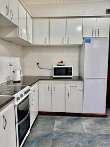 a kitchen with white cabinets and a microwave at Casa del Zanzibar in Zanzibar City