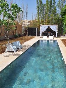 a swimming pool with chairs and a gazebo at loft B in Fez