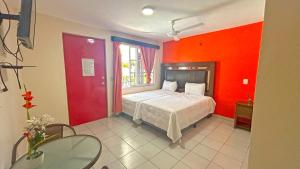a bedroom with red walls and a bed and a table at HOTEL REAL UCUM in Ocum +56 photos