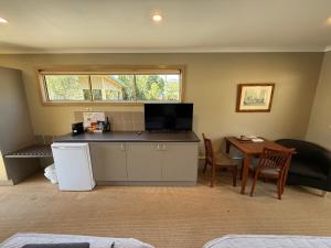 a room with a kitchen and a table with a television at Motel Strahan in Strahan