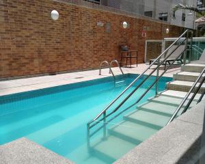 a swimming pool with stairs next to a brick wall at Book Santos Mar, Sol e Conforto no Unique 710 e 810 in Santos