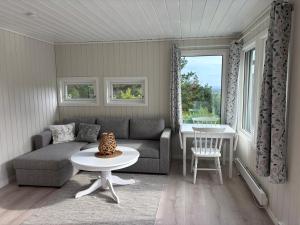 a living room with a couch and a table at Peaceful seaside cabin with guest house - large private outdoor areas and boat available on request in Eigebrekk
