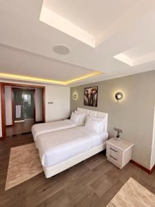 a bedroom with a large white bed and a table at Boynuz Hotels in Nyahururu
