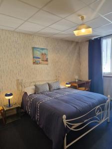 a bedroom with a bed with a blue blanket at Hôtel de la Gare - Morlaix in Morlaix