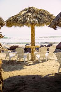 a group of chairs and an umbrella on the beach at PELÍCANOS Hotel & Beach Club in El Zapote