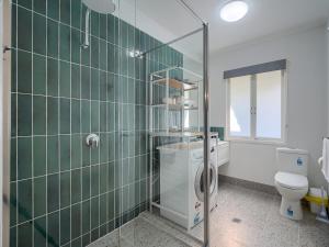 a green tiled bathroom with a toilet and a shower at Ocean Getaway in Hervey Bay +27 photos