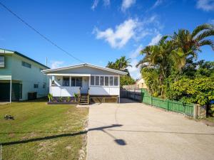 a white house with a fence and a yard at Ocean Getaway in Hervey Bay