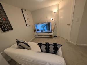 a living room with a white couch and a flat screen tv at Modern Private Suite - Quiet & Central Winnipeg in Winnipeg