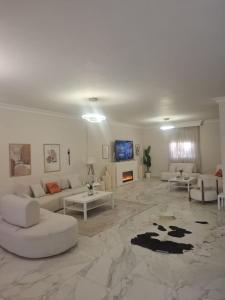 a living room with white furniture and a fireplace at Villa Casablanca in 6th Of October
