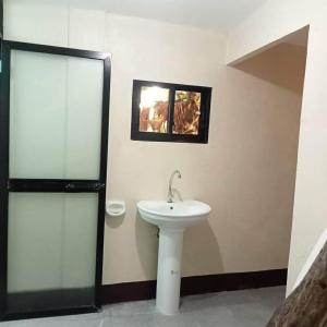 a bathroom with a white sink and a mirror at Moalboal Homestay VILLA in Tomonoy +14 photos