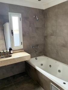 a bathroom with a bath tub and a sink at Casa Olivia in Luján