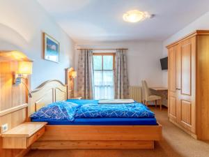 a bedroom with a blue bed and a window at Pension Blaiken M in Scheffau am Wilden Kaiser