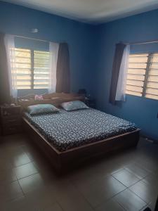 a bed in a room with blue walls and windows at Villa Frisi in Palimé