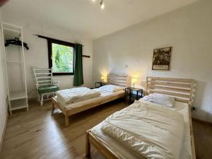 two beds in a room with two chairs and a window at Boogie House in Rendeux