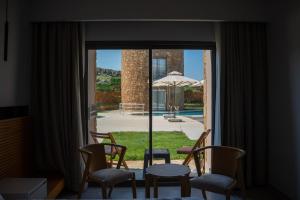 a room with a window with chairs and a table and an umbrella at Blue Inn Hotel in Gökçeada
