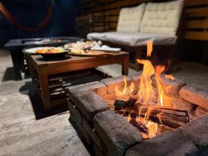 a fire pit in a living room with a table with food at グランコテージベンガルの森 in Nasu