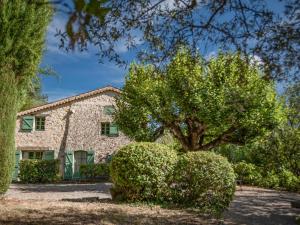 a stone house with a tree and bushes at Le Mas dormant in Fayence