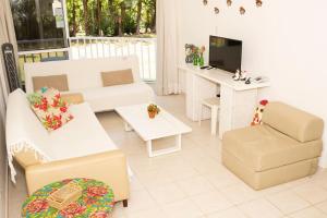 a living room with white furniture and a tv at Pé na areia - verdadeiro paraíso em Muro Alto in Porto De Galinhas