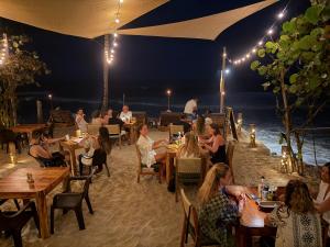 a group of people sitting at tables on the beach at night at Makao Beach Hotel in Palomino
