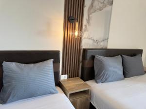 two beds with blue pillows in a hotel room at STANDART Premium in Ulcinj