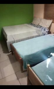 two beds in a room with green walls at Cirlene e Lyncon in Paranaguá