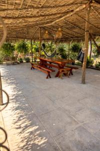 a picnic table under a straw roof at Chácara Sossego in Viçosa do Ceará