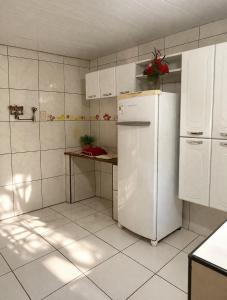 a kitchen with a white refrigerator and a table at Chácara Sossego in Viçosa do Ceará