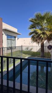 a pool with a fence and a palm tree at شاليه ماديرا in Hail