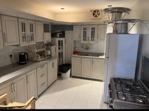 a kitchen with white cabinets and a refrigerator at شاليه ماديرا in Hail