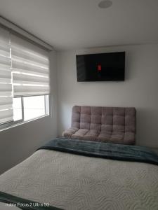 a bedroom with a large bed with a flat screen tv at Room cerca al aeropuerto #4 in Bogotá