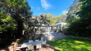 a house with a bench in the yard at Luxury Pearl Beach House with Private Heated Mineral Pool, Yoga Deck & Fire Pit in Pearl Beach