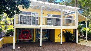 a yellow house with a car inside of it at Luxury Pearl Beach House with Private Heated Mineral Pool, Yoga Deck & Fire Pit in Pearl Beach +52 photos