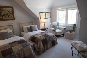a bedroom with two beds and a chair and a window at Gypsy by the Lake Bed and Breakfast in Sutton
