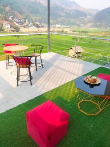 a patio with a table and chairs and grass at Hoa Sơn Tra Hotel in Mù Cang Chải