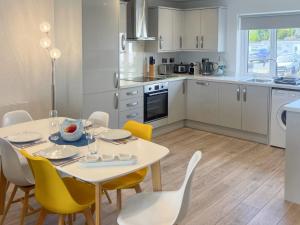 a kitchen and dining room with a table and chairs at The Holiday House in Benllech +10 photos