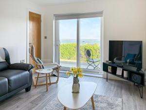 a living room with a couch and a tv at The Holiday House in Benllech