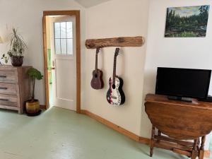 a room with a tv and a guitar hanging on the wall at Kinsol Hideaway in Shawnigan Lake