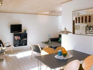 a living room with tables and chairs and a tv at 4 person holiday home in Allinge in Allinge