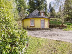 a small yellow house in the middle of a yard at Tinkerbell in Balnaboth