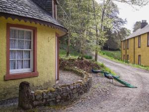 a peacock standing outside of a house next to a building at Tinkerbell in Balnaboth