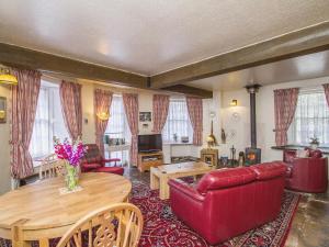 a living room with a red couch and a table at Tinkerbell in Balnaboth +6 photos