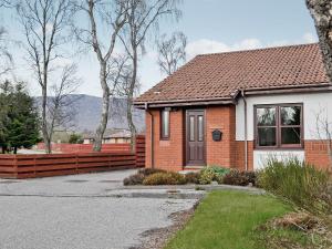 a brick house with a fence in front of it at Glenrothay in Aviemore