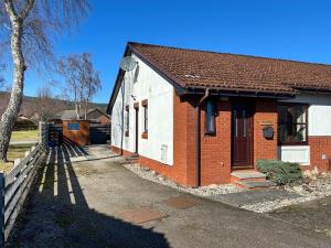 a red and white brick house with a tree at Glenrothay in Aviemore +4 photos