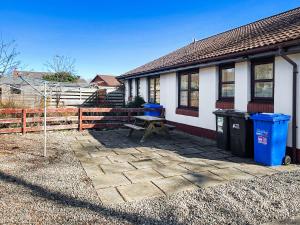 a house with a picnic table and two trash cans at Glenrothay in Aviemore