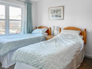 two beds sitting next to a window in a bedroom at Glenrothay in Aviemore