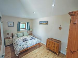 a bedroom with a bed and a wooden dresser at Stonechat Barn in Pancrasweek