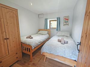 a small bedroom with two beds and a window at Stonechat Barn in Pancrasweek +2 photos