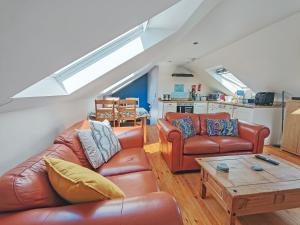 a living room with two leather couches and a table at Stonechat Barn in Pancrasweek